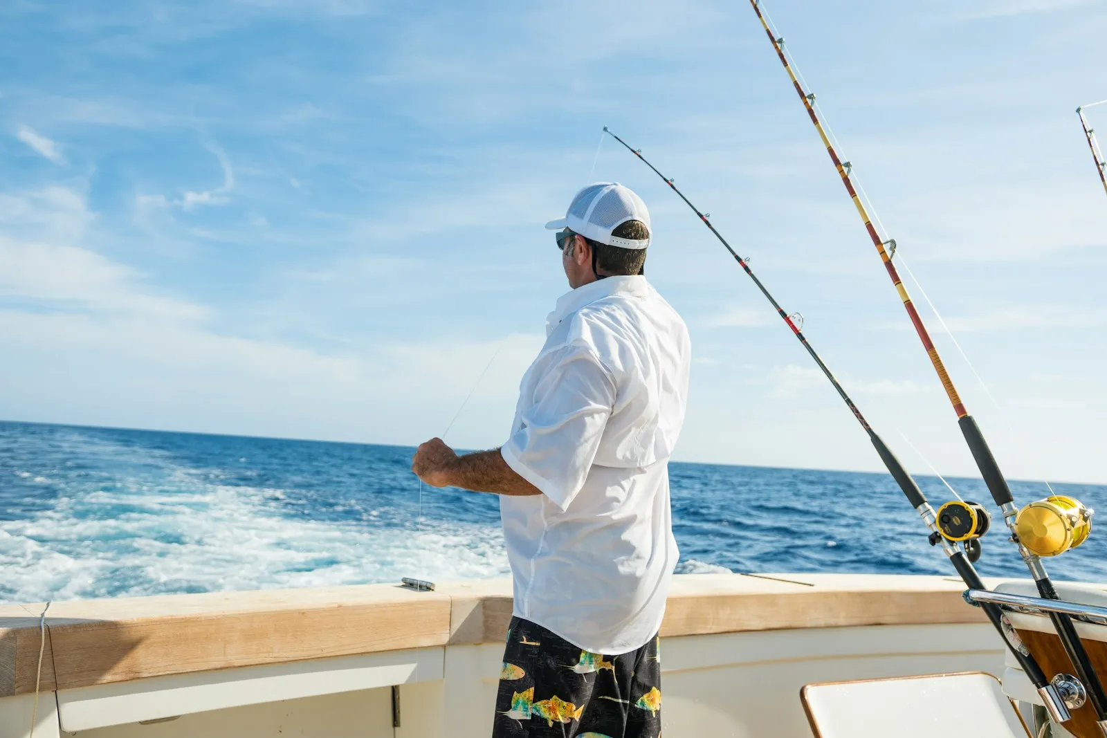 A fisherman standing beside trolling rods on a sport-fishing boat