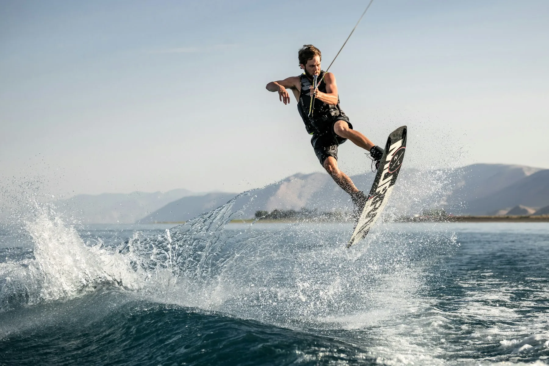 A wakeboarder in mid-jump behind a boat