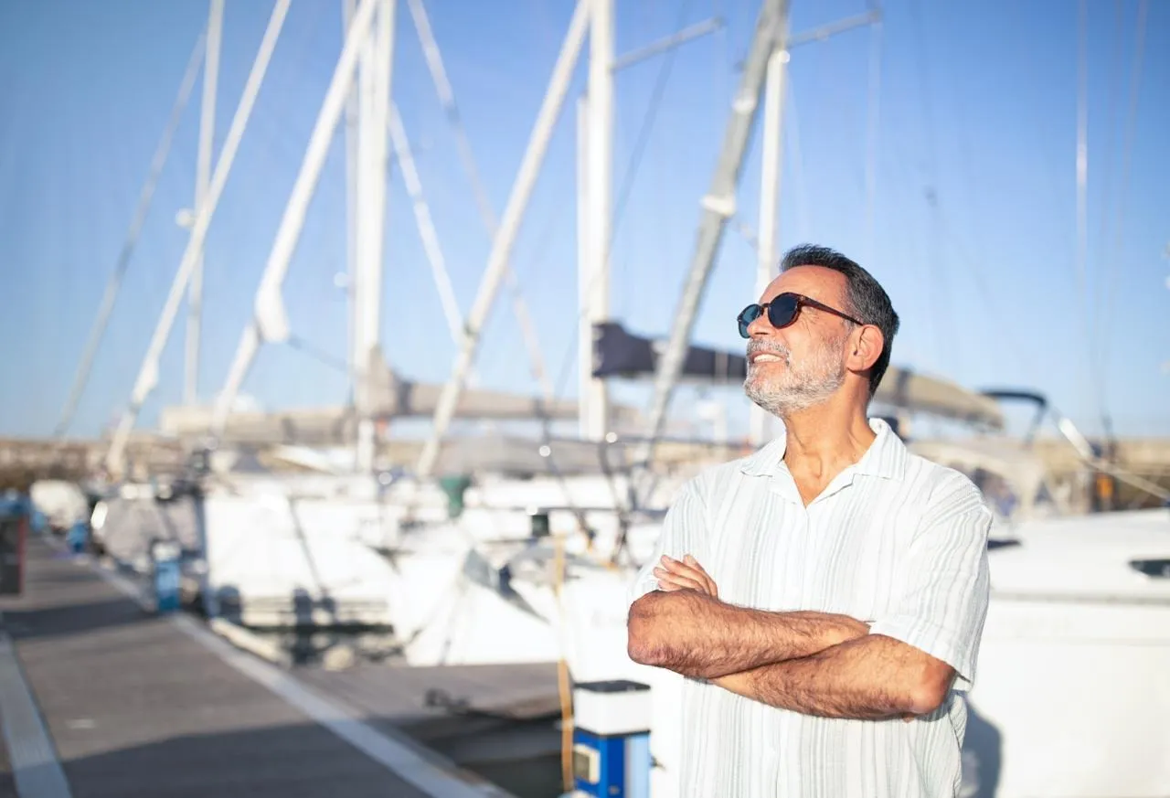 A confident entrepreneur with his arms crossed, looking out over a marina