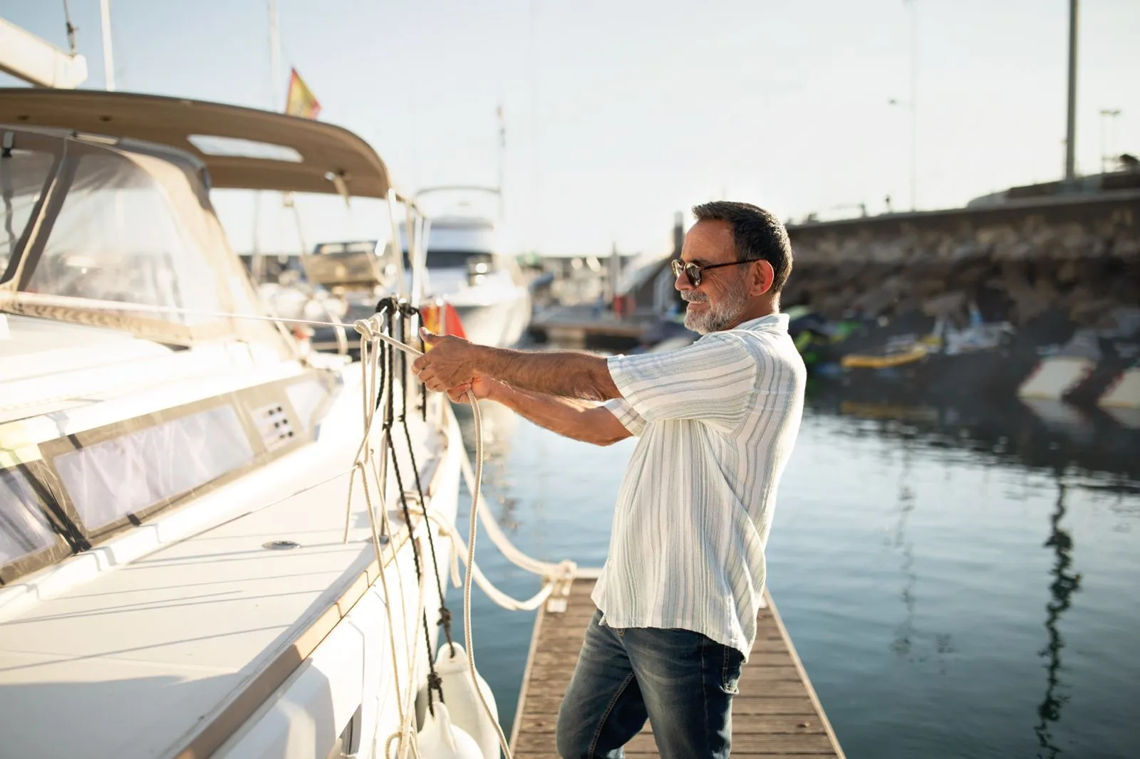 A man in sunglasses securing a boat to the dock at a marina